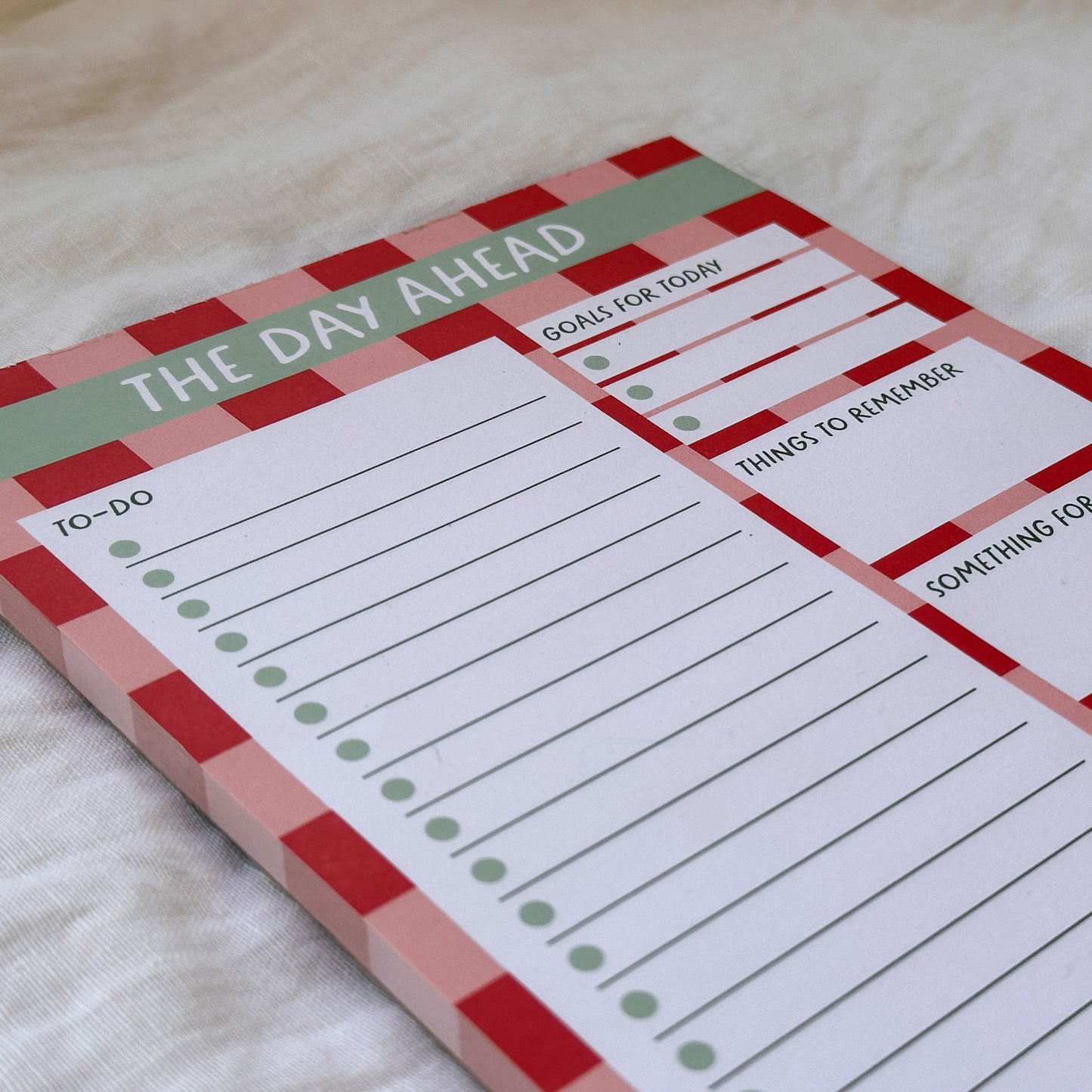 Notepad with checkered border and daily planner sections on a light background